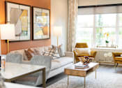 Thumbnail 2 of 20 - A modern living room with a grey couch, a coffee table, and two lamps.