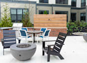 Thumbnail 16 of 20 - A patio with a fire pit and chairs.
