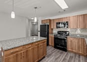 Thumbnail 14 of 19 - A kitchen with wooden cabinets and a black refrigerator.