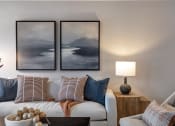 Thumbnail 7 of 35 - a living room with two paintings on the wall and a white couch with pillows at The Austin Apartment Homes, Deptford, 08096