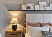 Thumbnail 16 of 35 - a bedroom with a bed and a nightstand with a lamp and pictures on the at The Austin Apartment Homes, Deptford, NJ, 08096