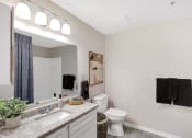 Thumbnail 22 of 35 - a bathroom with a toilet and a sink and a mirror at The Austin Apartment Homes, New Jersey, 08096