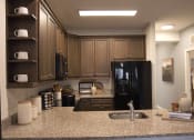 Thumbnail 12 of 36 - a kitchen with a granite counter top and a black refrigerator  at Carillon Woods, Millsboro, 19966