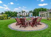 Thumbnail 22 of 31 - A set of four brown chairs are arranged around a circular table in a grassy area.