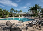 Thumbnail 17 of 20 - a swimming pool with chairs and a house in the background at Champions Walk Apartment Homes, Bradenton, Florida