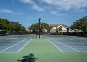 Thumbnail 18 of 20 - a tennis court with apartments in the background at Champions Walk Apartment Homes, Bradenton, Florida