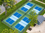 Thumbnail 16 of 20 - A tennis court is surrounded by a fence and has a small pavilion.