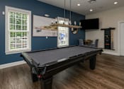 Thumbnail 18 of 31 - A pool table in a room with blue walls and wood flooring.