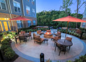 Thumbnail 24 of 26 - a patio with tables and umbrellas and a fire pit at Merion Riverwalk Apartment Homes, Shelton, CT, 06484