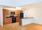 Thumbnail 27 of 27 - an empty kitchen with wooden cabinets and black appliances at Merion Stratford Apartment Homes, Stratford, CT