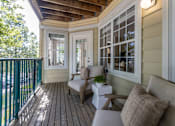 Thumbnail 13 of 28 - A small balcony with a couch, chair and table.