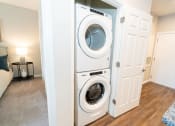 Thumbnail 10 of 26 - a front loading washer and dryer in a living room at Merion Riverwalk Apartment Homes, Shelton, 06484