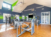 Thumbnail 4 of 27 - a gym with cardio equipment and weights in a building with windows at Merion Stratford Apartment Homes, Stratford, CT, 06614