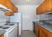 Thumbnail 25 of 27 - A kitchen with white appliances and wooden cabinets.