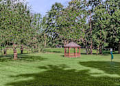 Thumbnail 5 of 27 - A gazebo sits in the middle of a grassy field.