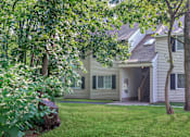 Thumbnail 13 of 27 - A house with a green lawn and trees in front.