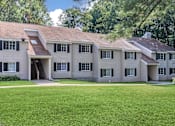 Thumbnail 4 of 27 - A large house with a green lawn in front.