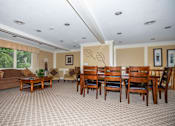 Thumbnail 7 of 27 - A living room with a brown couch, a coffee table, and a dining table with chairs.