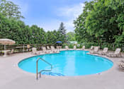 Thumbnail 11 of 20 - A large outdoor swimming pool surrounded by lounge chairs and trees. at North Pointe Apartments, Clifton Park