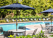 Thumbnail 8 of 24 - a swimming pool with tables and chairs and umbrellas at Merion Milford Apartment Homes, Milford, 06460