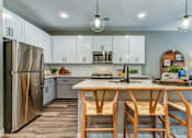 Thumbnail 3 of 20 - A modern kitchen with a wooden table and chairs.