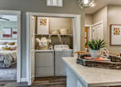Thumbnail 5 of 20 - A laundry room with a washer and dryer is open to a bedroom.