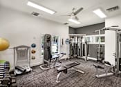 Thumbnail 10 of 34 - A gym with a variety of equipment including a treadmill, weights, and a bench.