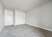 Thumbnail 7 of 28 - a bedroom with two doors and a carpeted floor