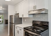 Thumbnail 15 of 41 - an empty kitchen with white cabinets and a stove and refrigerator