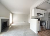 Thumbnail 5 of 28 - a living room with a fireplace and a kitchen with a stove and refrigerator