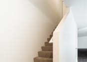 Thumbnail 22 of 41 - a carpeted staircase in a home with white walls and wood floors