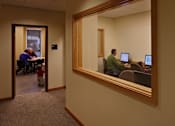 Thumbnail 18 of 27 - A man is sitting in front of a computer in a room with a mirror on the wall.
