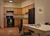 Thumbnail 20 of 27 - A kitchen with a black refrigerator and wooden cabinets.