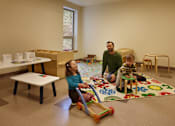 Thumbnail 16 of 27 - A man and two children playing with toys in a room.