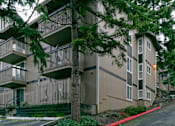 Thumbnail 2 of 5 - Apartment building with balconies and trees in front.