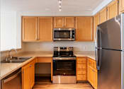 Thumbnail 20 of 21 - A kitchen with wooden cabinets and stainless steel appliances.