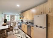 Thumbnail 2 of 5 - A kitchen with a refrigerator, sink, and dining table.