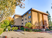 Thumbnail 1 of 18 - A large building with a parking lot in front of it.