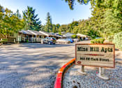 Thumbnail 1 of 9 - A sign for Mine Hill Apts stands in front of a parking lot.