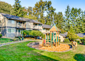 Thumbnail 5 of 9 - A playground with a green swing set is in the foreground of a grassy area.
