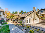 Thumbnail 4 of 24 - A house with a grey roof and a white door is surrounded by a green lawn.