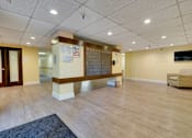 Thumbnail 7 of 18 - A spacious room with wooden flooring and a television mounted on the wall.