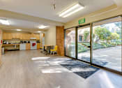 Thumbnail 6 of 18 - A kitchen area with a dining table and chairs is visible through a glass door.