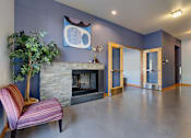 Thumbnail 9 of 27 - A living room with a fireplace and a painting on the wall.