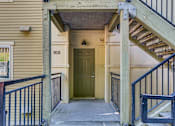 Thumbnail 14 of 33 - A yellow house with a green door and a staircase leading to the entrance.