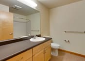Thumbnail 21 of 22 - A bathroom with a toilet, sink, mirror, and a towel bar.