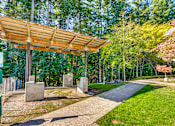 Thumbnail 13 of 24 - A wooden structure with a roof is in the middle of a grassy area.