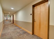 Thumbnail 20 of 22 - A hallway with a brown door and carpeted floor.