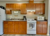 Thumbnail 15 of 17 - A kitchen with wooden cabinets and a white stove.
