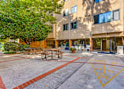 Thumbnail 17 of 18 - A building with a tree in front of it and a picnic table in front of the building.